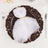 Elegant white napkin tied on an ornate brown plate.