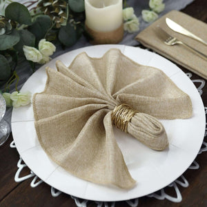 Elegant beige linen napkin elegantly folded on a white plate with gold utensils.