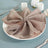 Elegant taupe napkin with copper ring elegantly arranged on a plate.