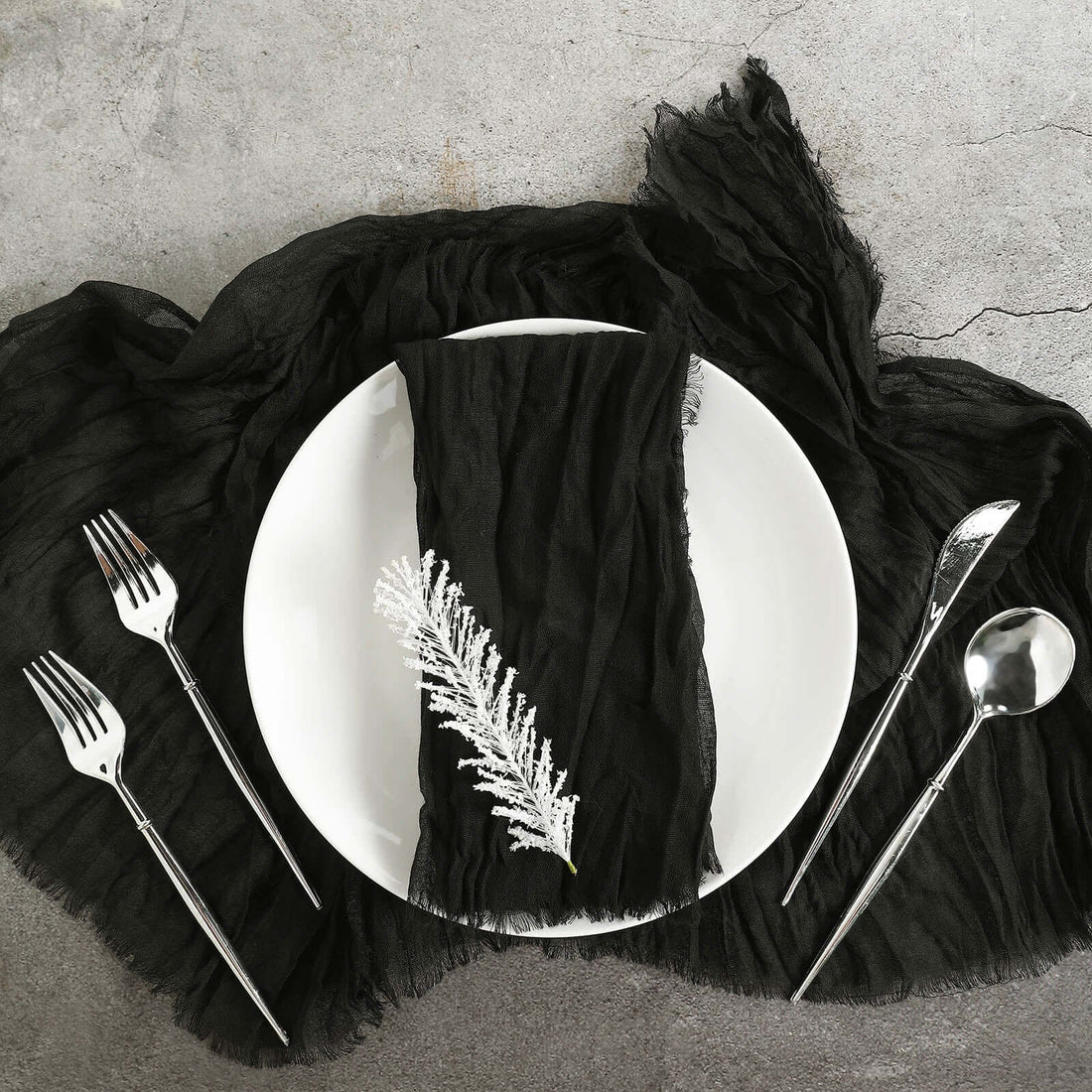 Elegant black table setting with fork, spoon, and textured napkin.