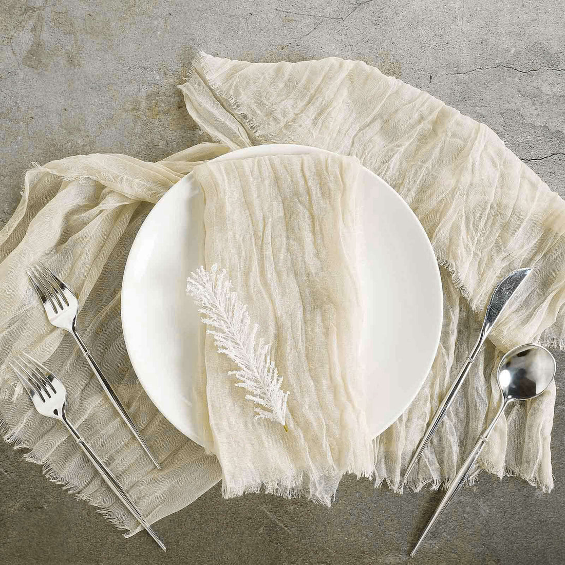 Elegant table setting with cream linen, white plate, and silver utensils.
