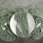 Elegant green linen napkin on a white plate with silver cutlery on textured surface.