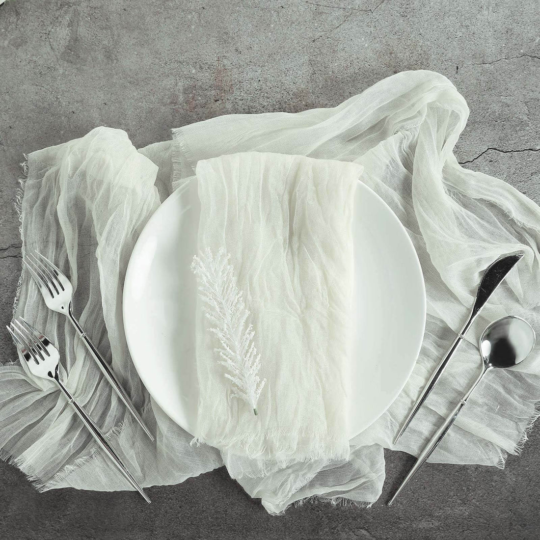 Elegant table setting with white plate, linen napkin, and silver cutlery.