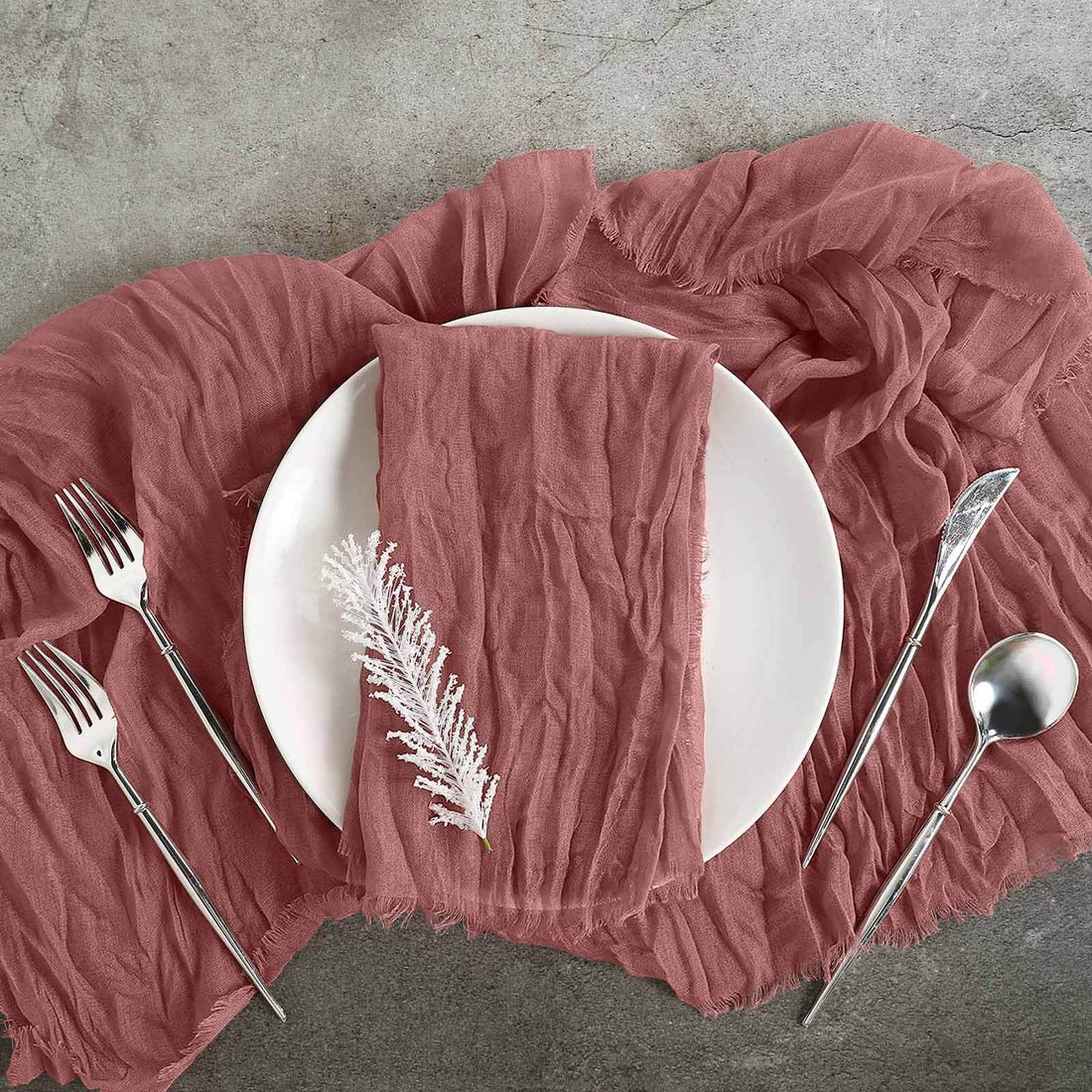 Rose pink textured tablecloth with white plate and silver cutlery arrangement.