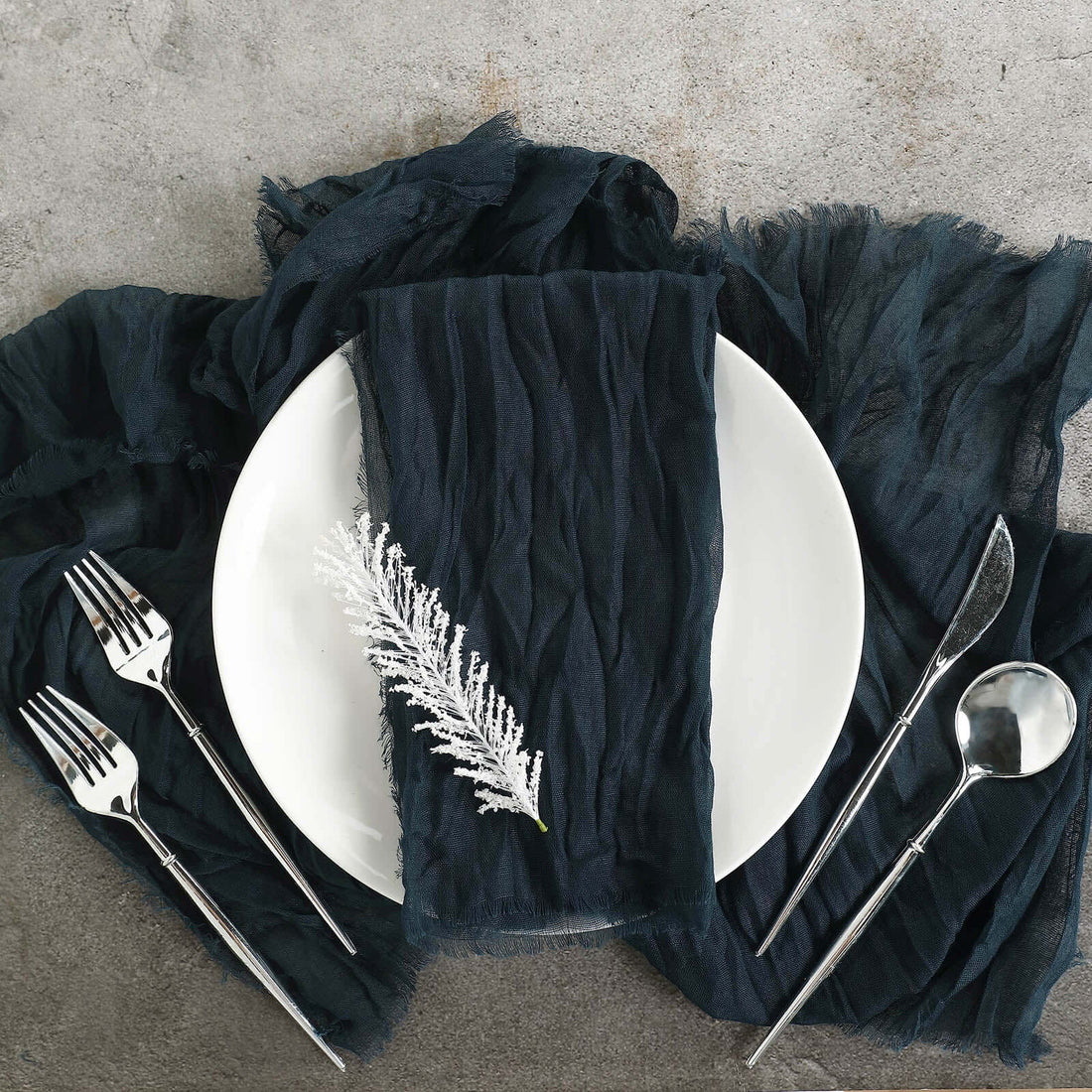 Elegant dining setup with navy napkin, white plate, and silver utensils.