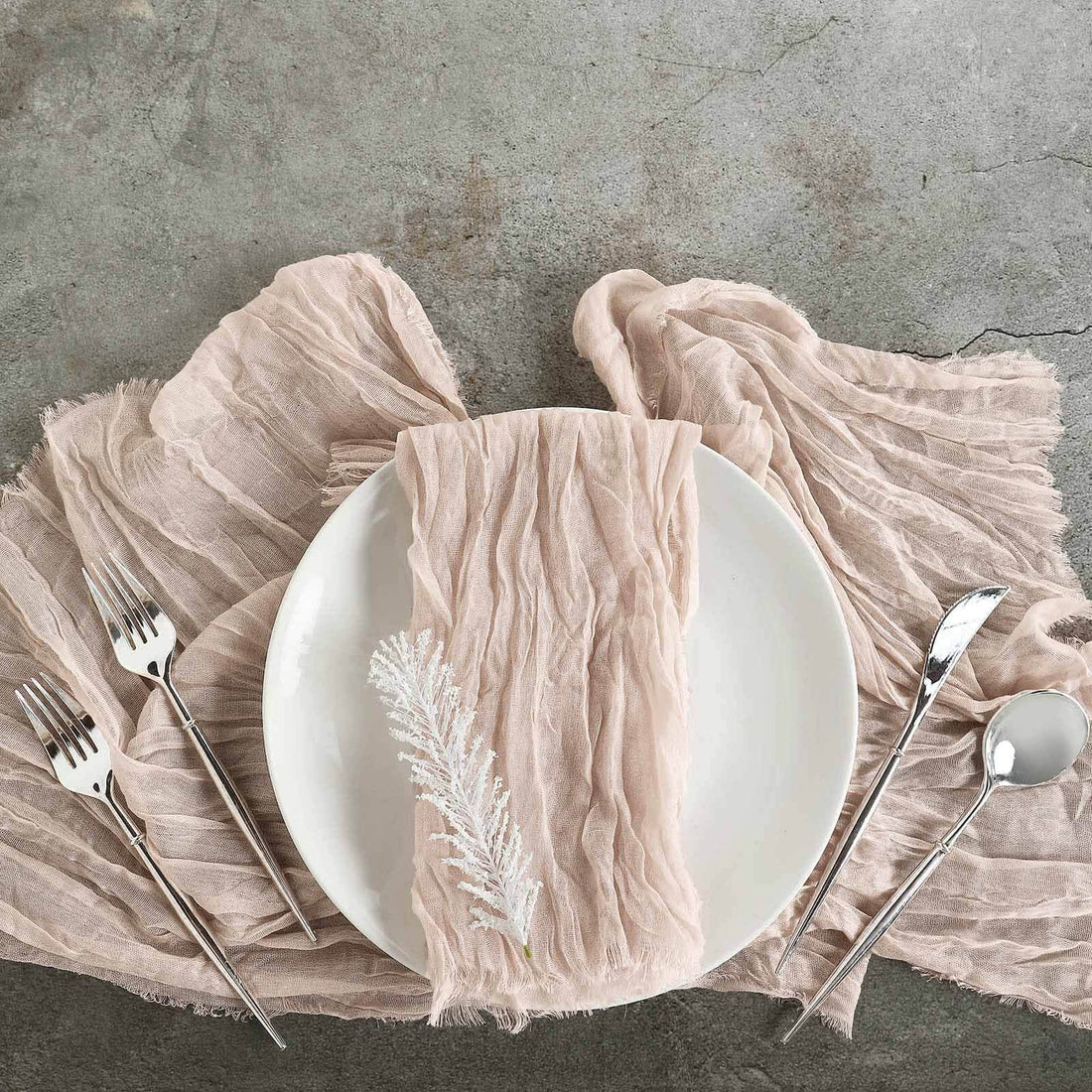 Elegant pink linen napkin on a white plate with silver cutlery.