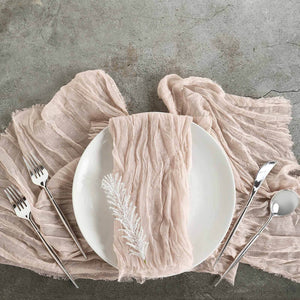 Elegant pink linen napkin on a white plate with silver cutlery.