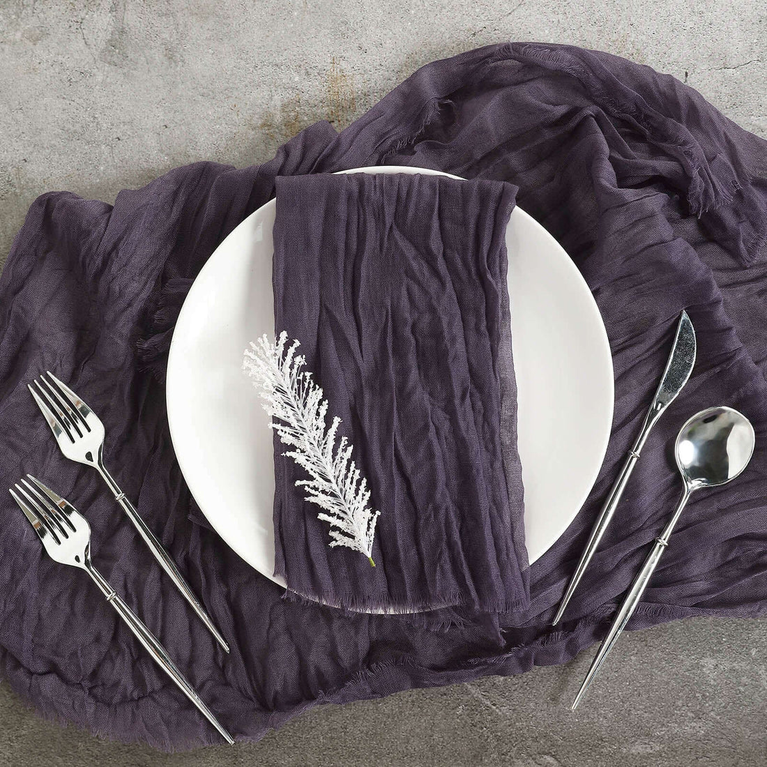 Elegant purple table setting with a textured napkin and silver cutlery.