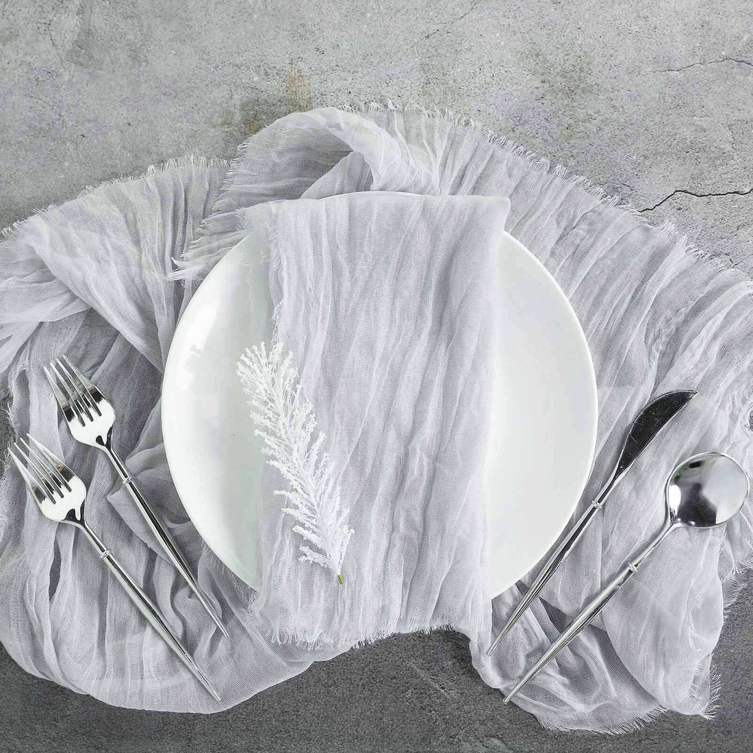 Elegant table setting with silver cutlery and a textured gray tablecloth.