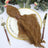 Brown textured napkin with a gold ring on a white plate, surrounded by elegant tableware.