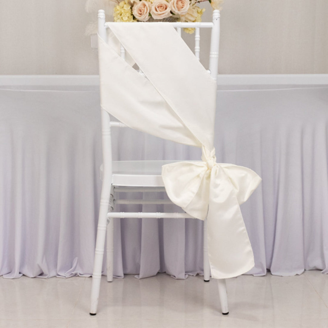Elegant white chair sash tied in a bow for wedding decor.