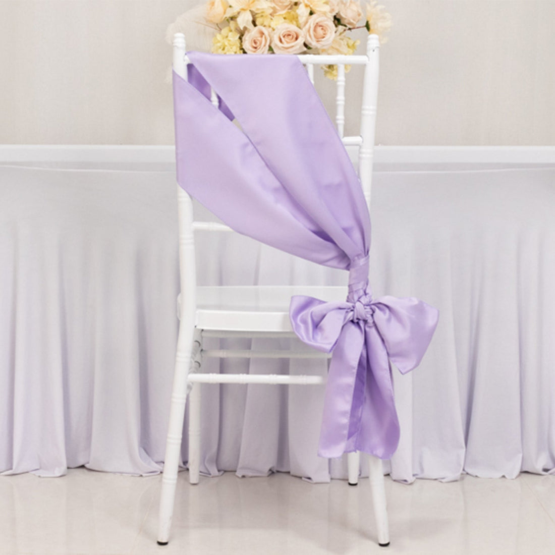 Lavender satin chair ribbon bow on a white chair.
