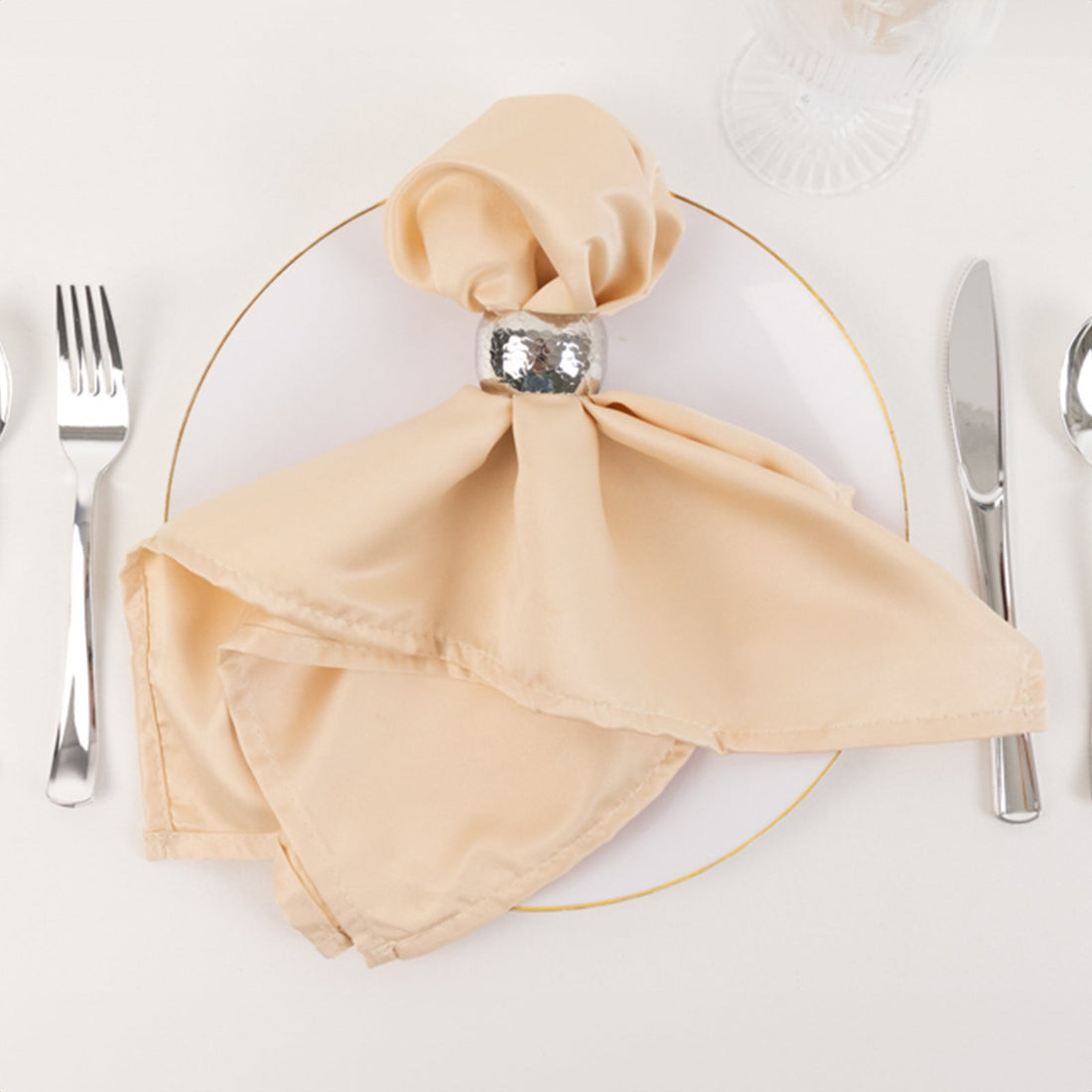 Elegant beige napkin with silver napkin ring on a dinner plate.