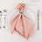 Elegant pink napkin with a silver ring on a white plate, set for dining.