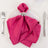 Pink napkin elegantly folded on a plate with silver napkin ring.