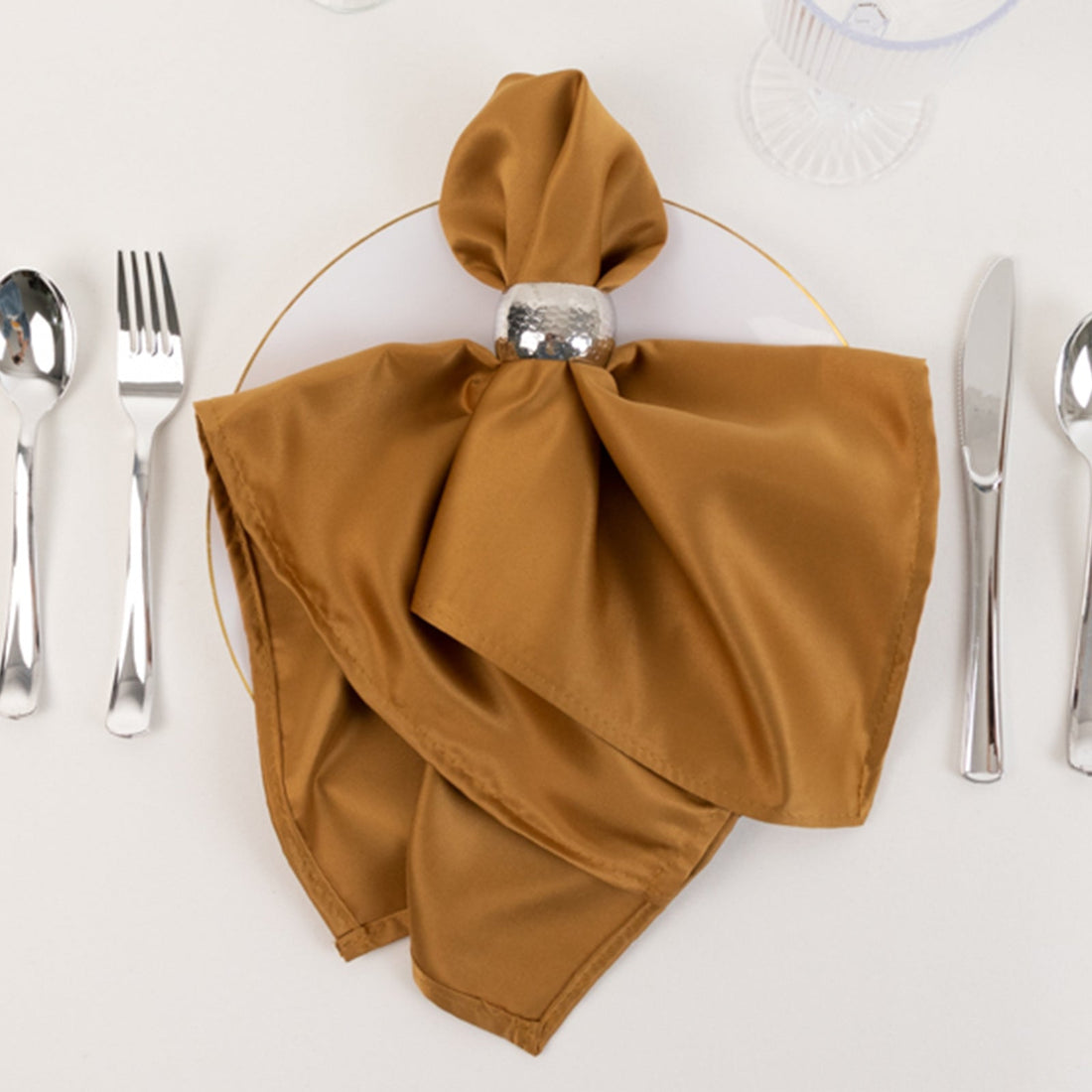 Elegant brown satin napkin tied with a silver ring on a dinner plate.