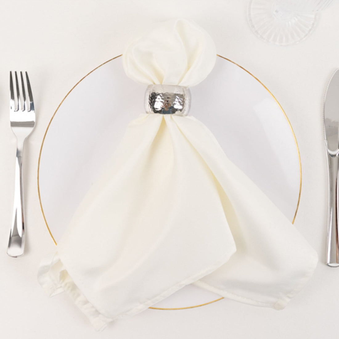 Elegant white napkin with silver ring on a white plate.