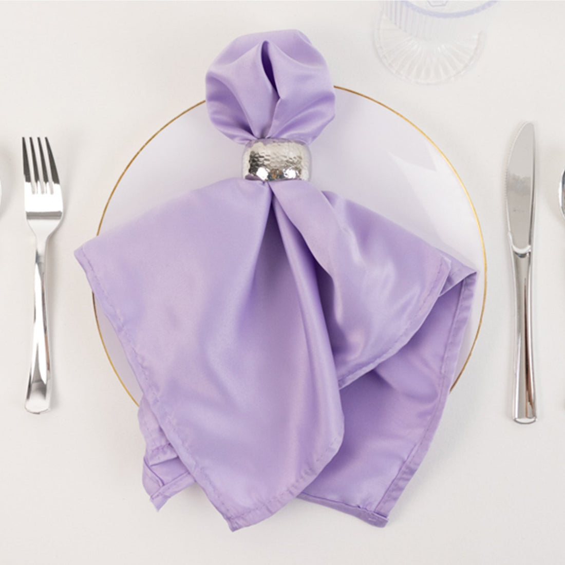 Lavender satin napkin elegantly styled on a white plate with silver ring.