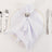 Elegant white napkin folded on a gold-rimmed plate, surrounded by silver cutlery.