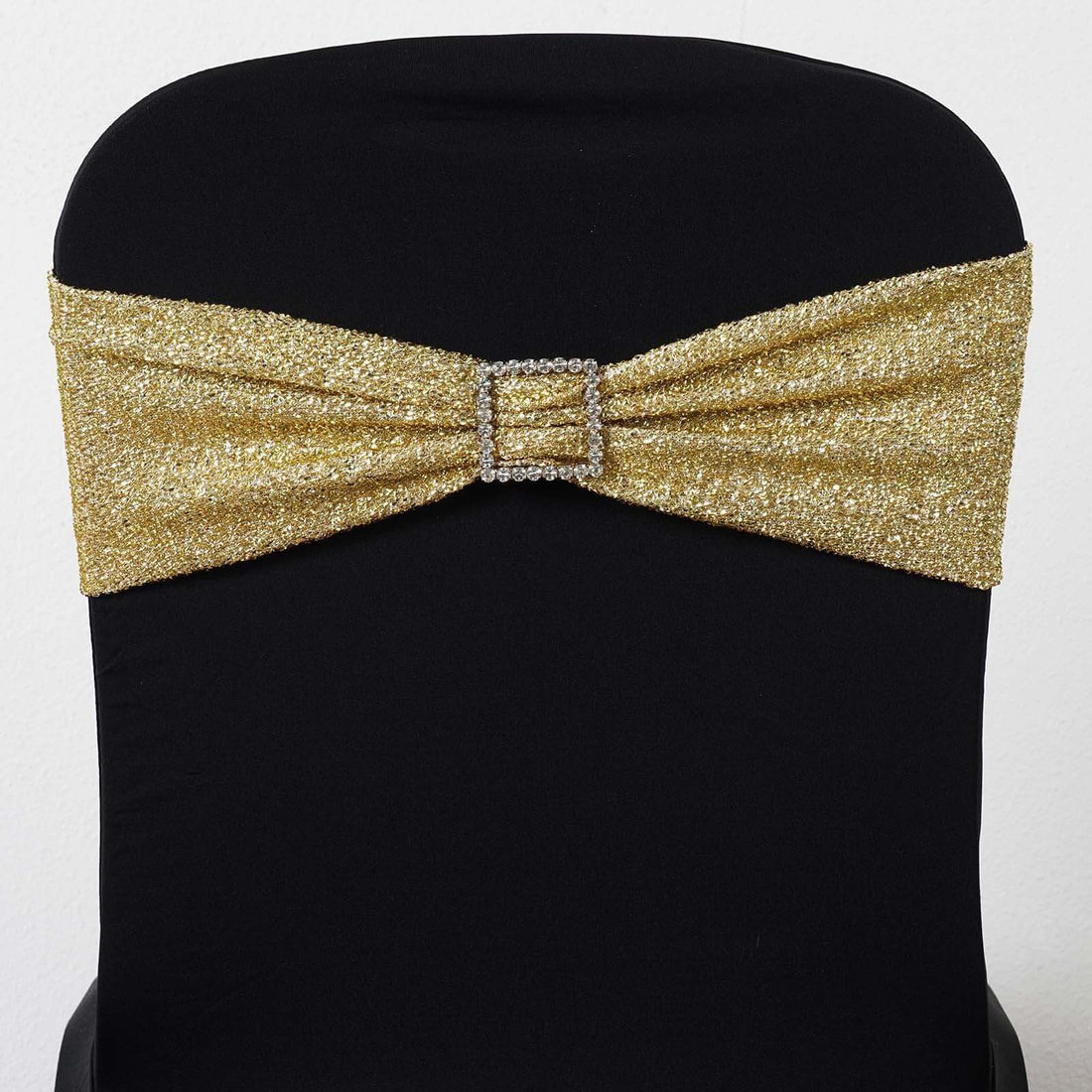 Gold sequin chair sash with rhinestone buckle on a black chair.
