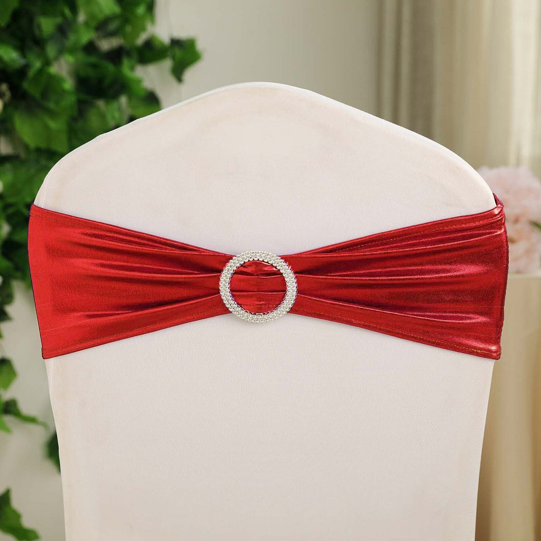 Red satin chair sash with rhinestone buckle for elegant decor.