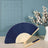 Navy blue folding fan with wooden handle and decorative pattern against a soft background.
