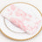 Pink floral napkin on a decorative gold-rimmed plate.