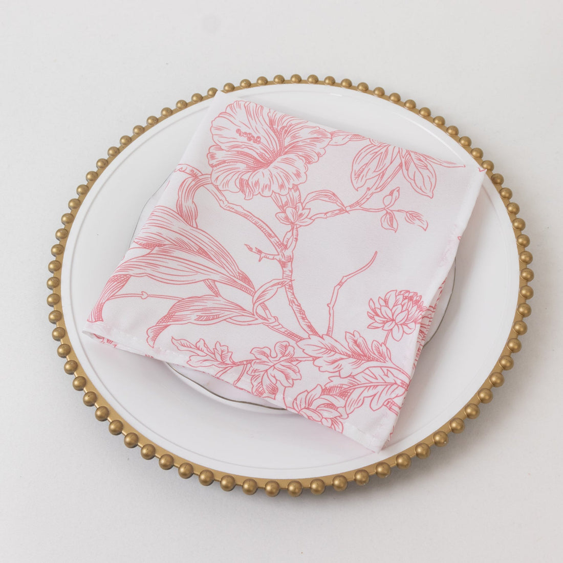 Pink floral napkin on a decorative plate.
