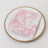 Pink floral napkin on a decorative plate.