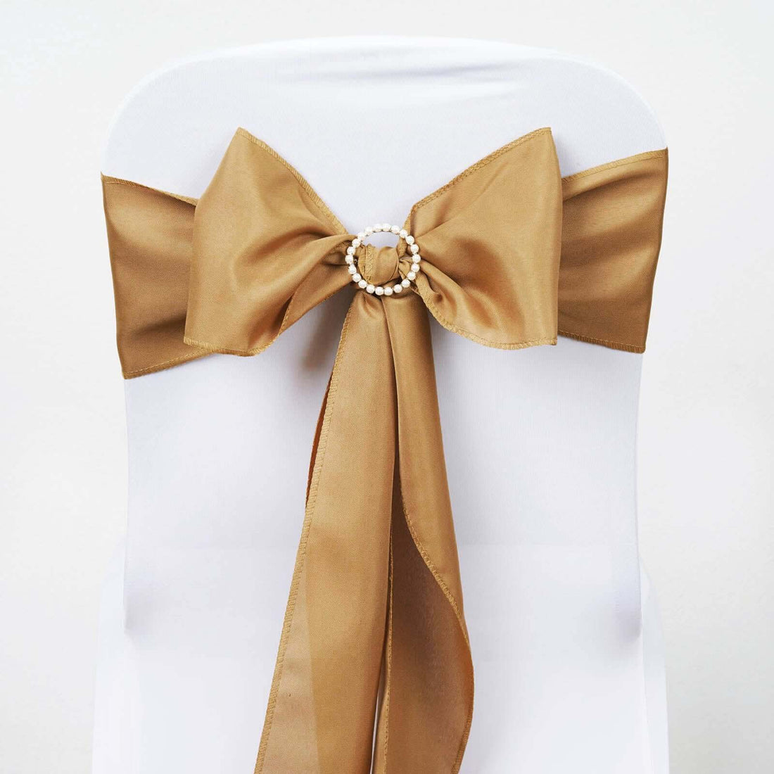 Gold satin chair sash with pearl embellishment on a white chair