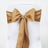 Gold satin chair sash with pearl embellishment on a white chair