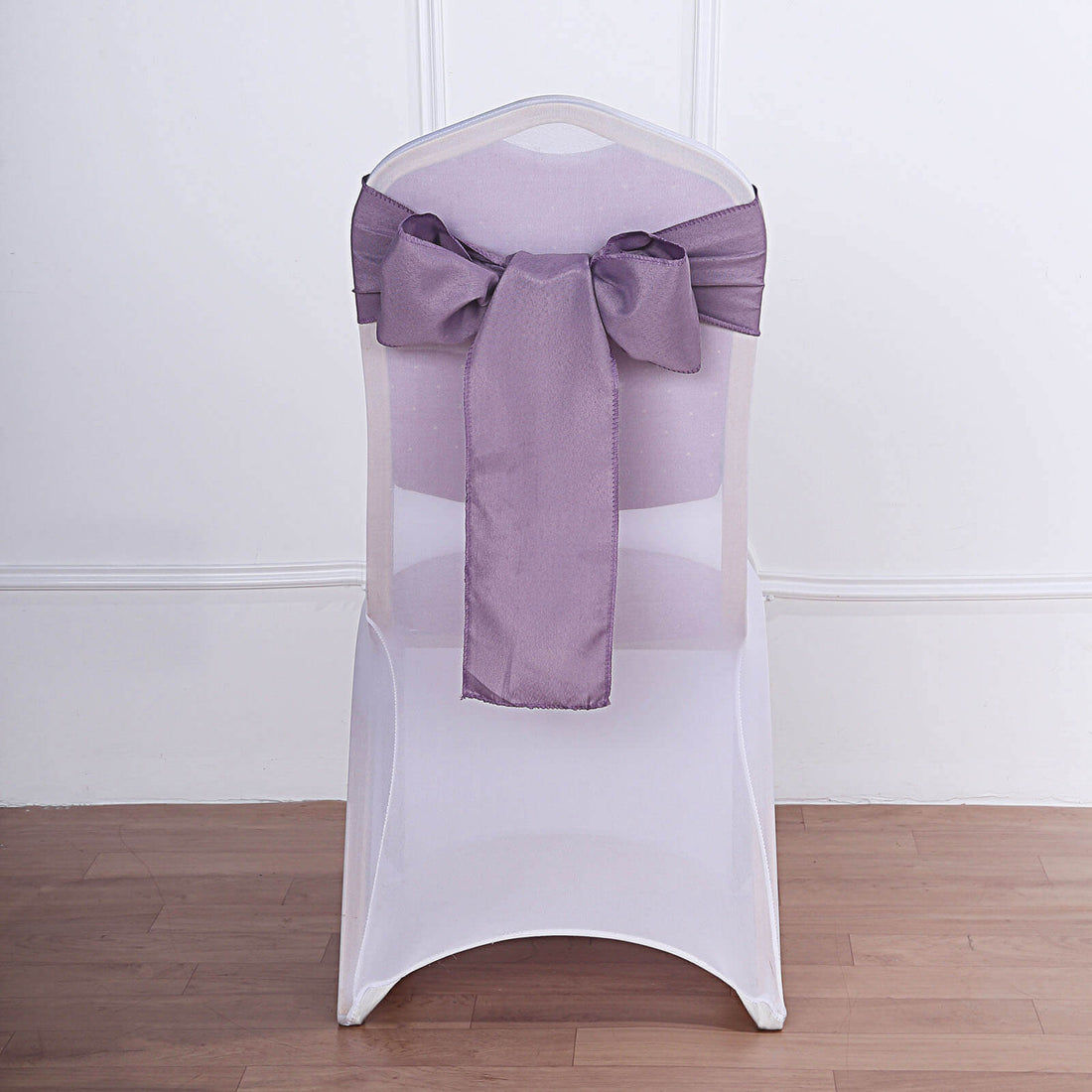 White chair with purple satin bow on a plain background