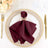 Burgundy napkin with gold butterfly ring on an elegant dinner plate