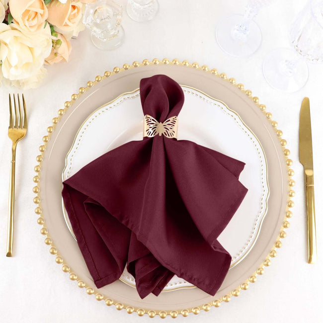 Burgundy napkin with gold butterfly ring on an elegant dinner plate