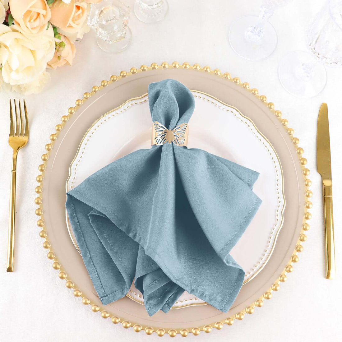 Elegant teal napkin with decorative holder on a stylish dinner plate.