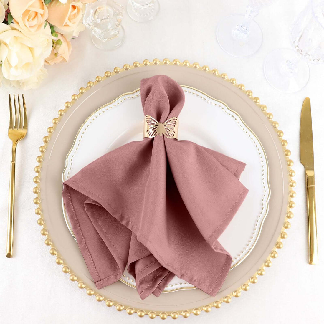 Elegant mauve napkin tied with a decorative clip on a styled dinner plate.