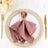 Elegant mauve napkin tied with a decorative clip on a styled dinner plate.