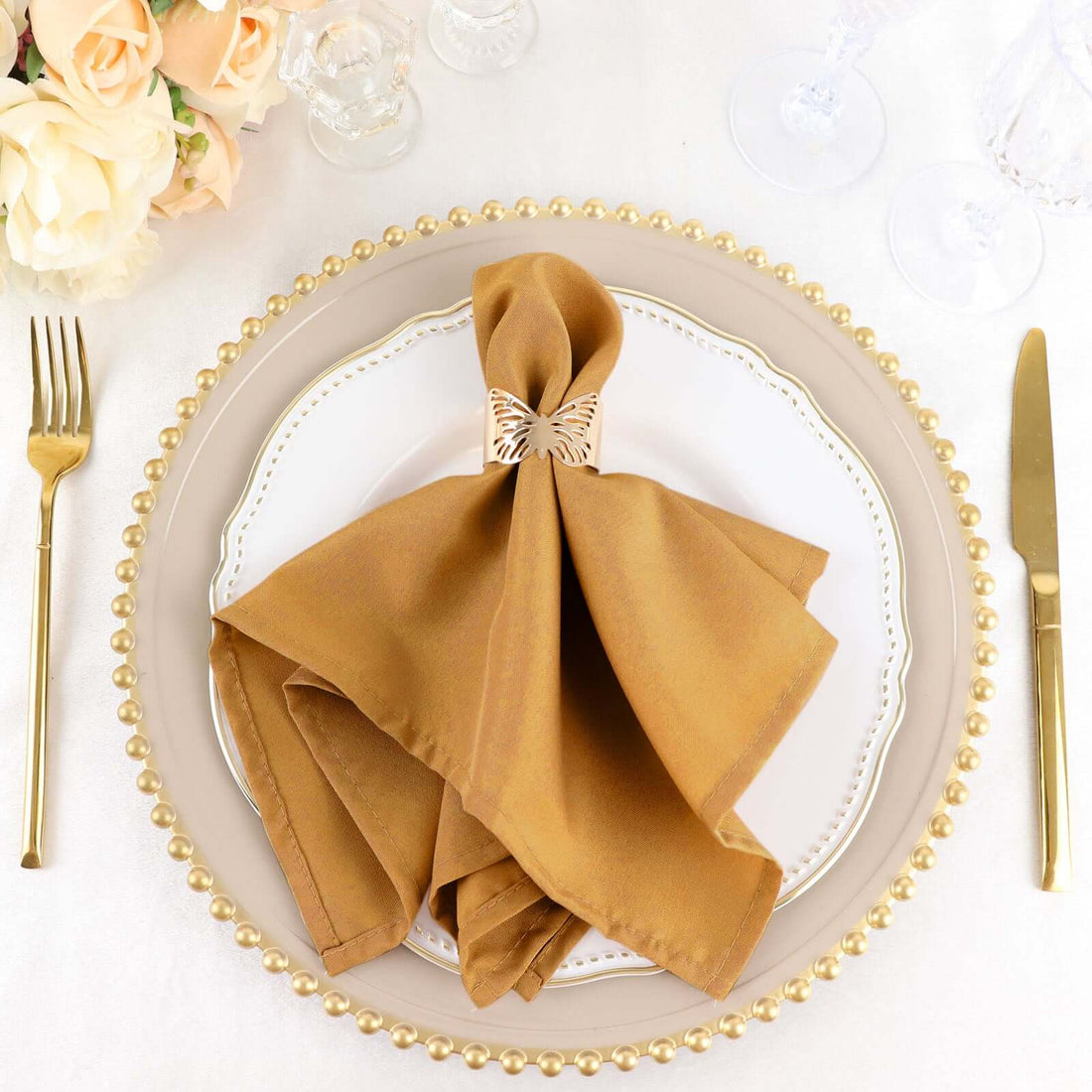 Elegant brown napkin elegantly folded on a decorative dinner plate with gold trim.