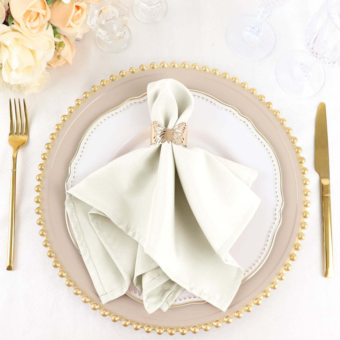 Elegant table setting with a satin napkin and decorative ring.
