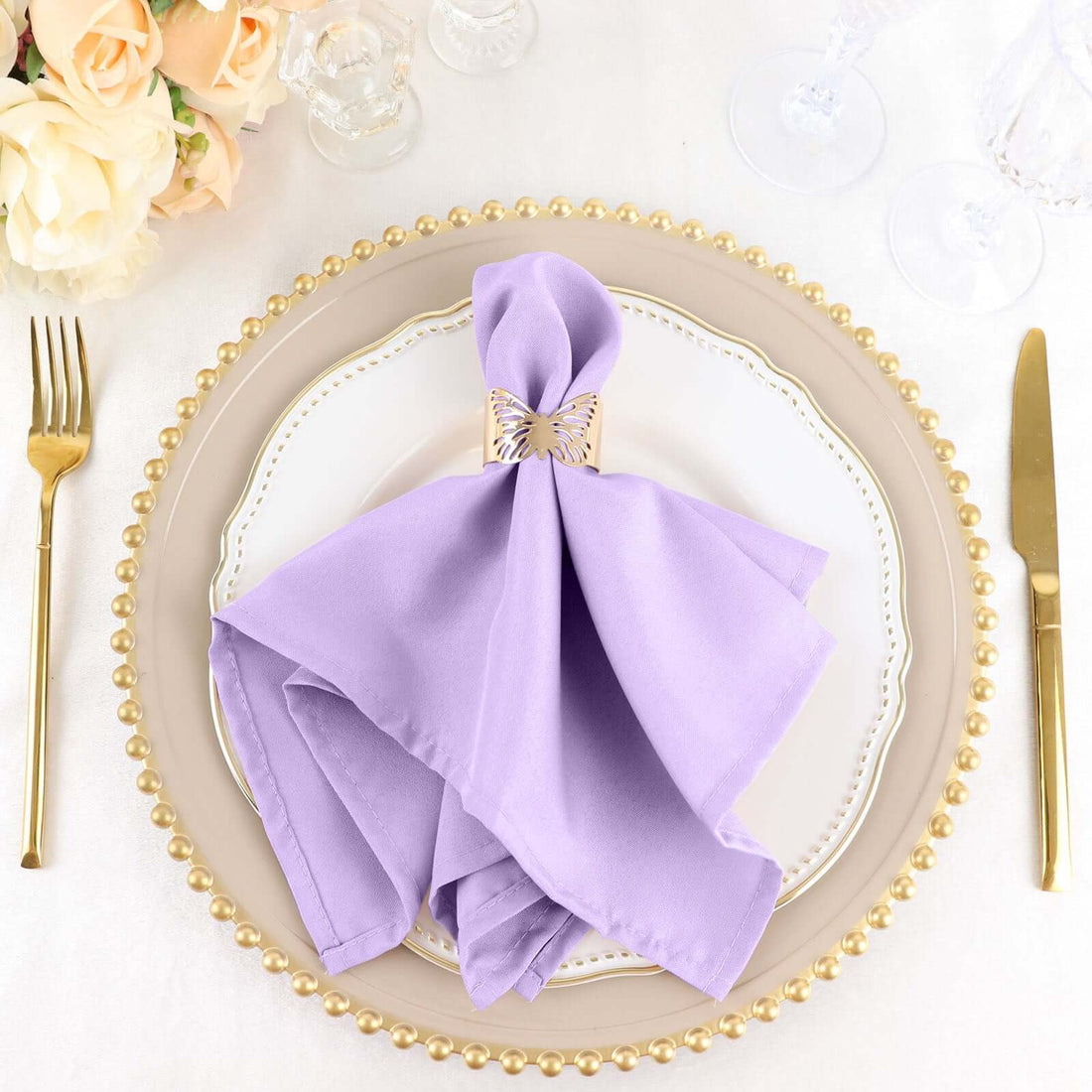 Lavender napkin elegantly folded on a decorative plate with a gold napkin holder.
