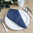 Denim napkin elegantly folded on a white plate with cutlery.