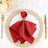 Red napkin elegantly arranged on a decorative plate with gold accents.