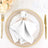 Elegant white napkin with gold ring on a decorative plate, set for dining.