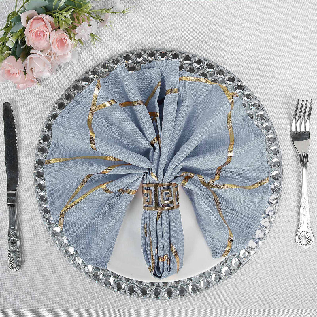Elegant blue napkin with gold stripes on a decorative plate setting.