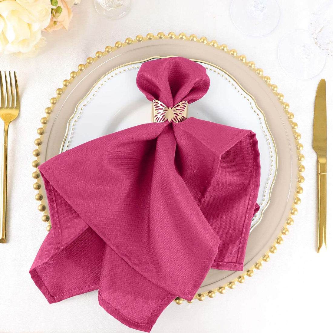 Elegant magenta napkin with butterfly holder on a decorative plate.