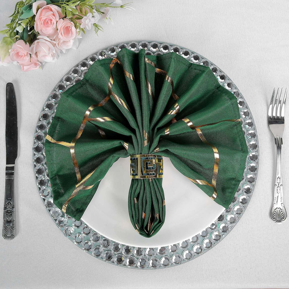 Elegant green napkin styled with gold accents on a decorative plate.