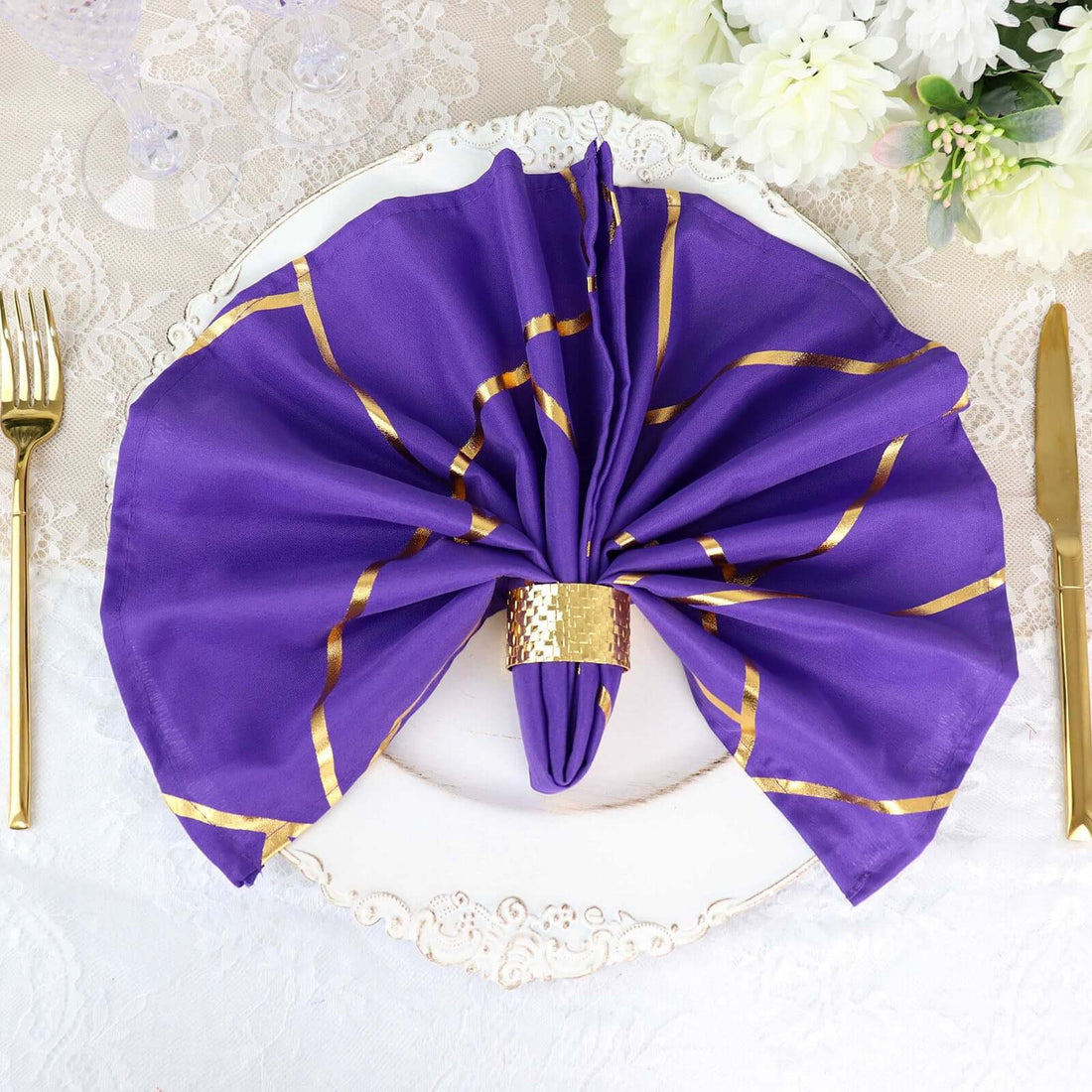 Purple napkin with gold accents elegantly styled on a white plate.