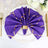 Purple napkin with gold accents elegantly styled on a white plate.