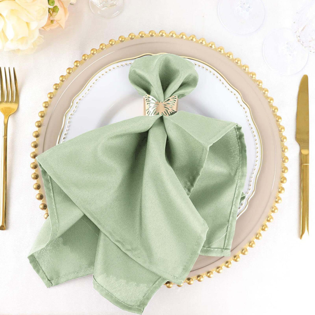 Elegant green napkin folded with a decorative ring on a festive dinner plate.