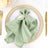 Elegant green napkin folded with a decorative ring on a festive dinner plate.